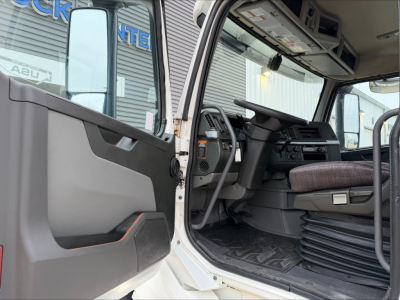 Truck cab interior of a 2019 Volvo VNL300 showing driver seat, steering wheel, dashboard, and open door.