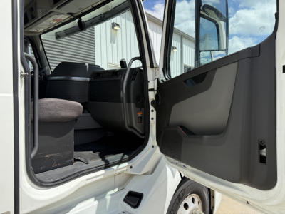 Volvo VNL300 cab interior view from open driver door showing steering wheel and seat area.