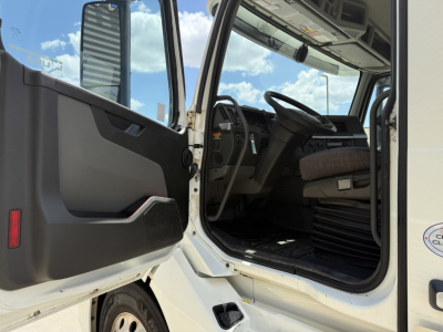  Volvo VNL300 cab interior showing driver seat and steering wheel with open door, dashboard, and steps visible.
