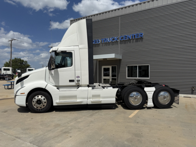 Volvo VNL300 daycab tractor in front of dealership showing sleeper cab, side view, white exterior, three rear axles, stock number B3451P.