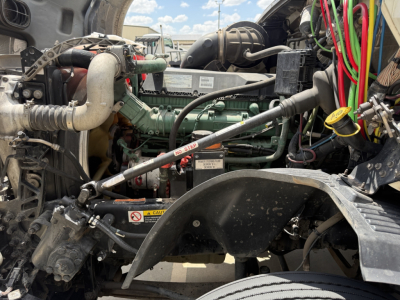Engine bay of a 2019 Volvo VNL300 daycab showing green Volvo engine, hoses, wiring, and nearby components in view.