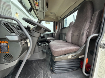 Cab interior of a 2019 Volvo VNL300 conventional daycab showing driver seat, steering wheel, and dashboard with label panels.