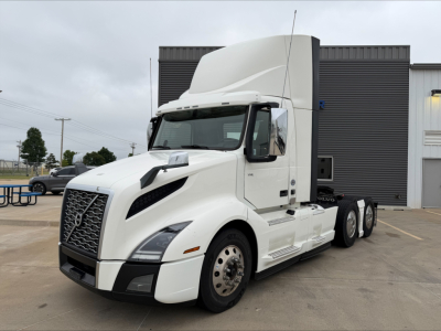 Volvo VNL300 tractor cab in white, front-left view showing aerodynamic hood, large grille, and side mirrors; chrome fuel tanks and step rails visible; no text readable on parts.