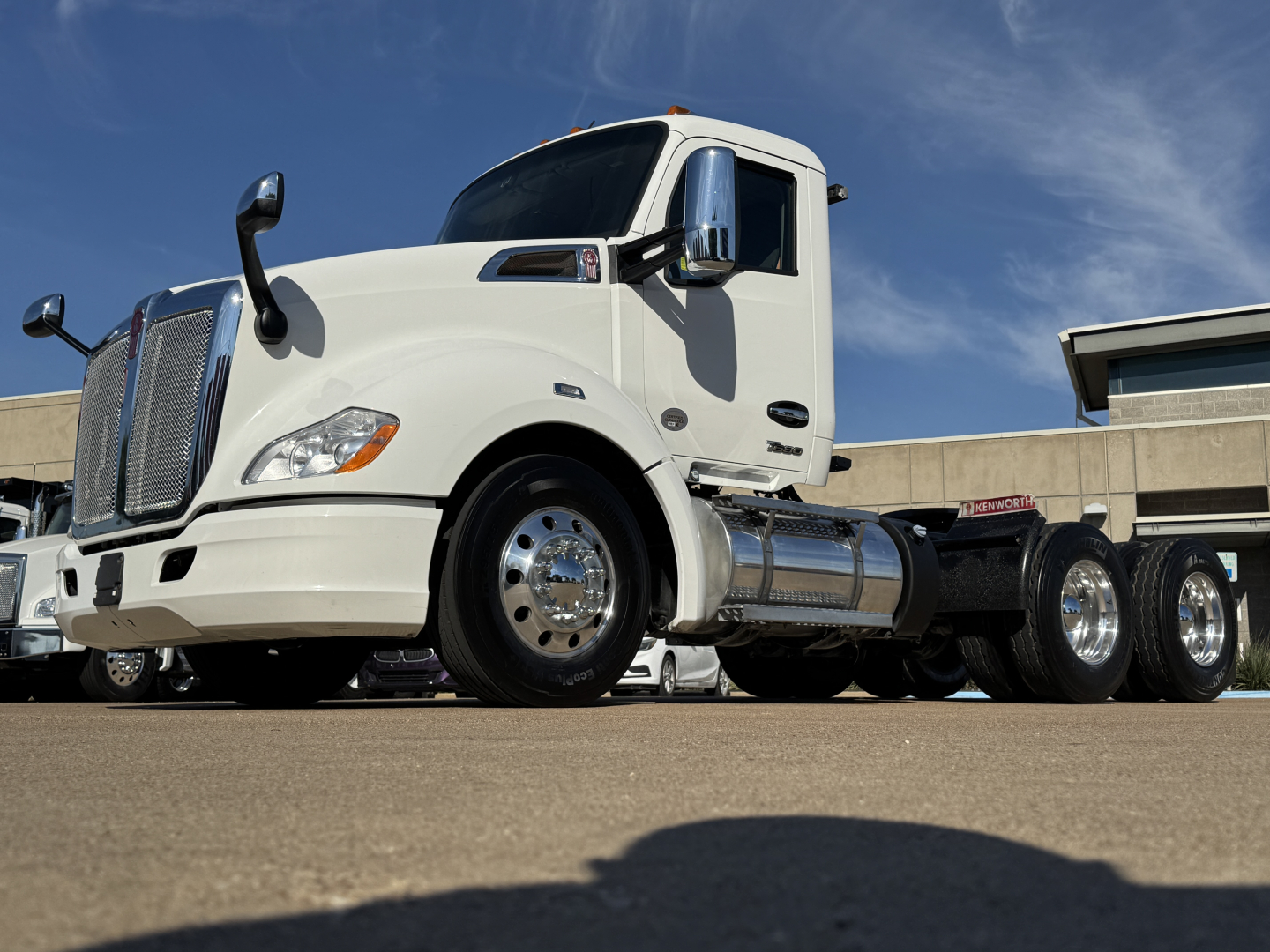 Kenworth T680 2022 conventional daycab truck side view showing front grille, dual rear axles, chrome fuel tanks, and large side mirrors.