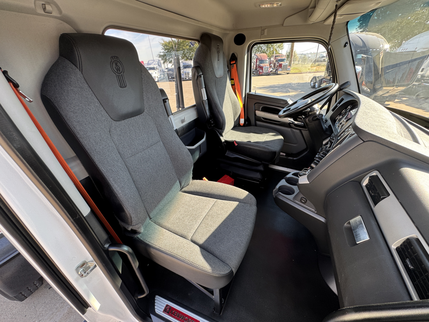 Truck cab interior of a 2022 Kenworth T680 showing front seats and dashboard from passenger side view.