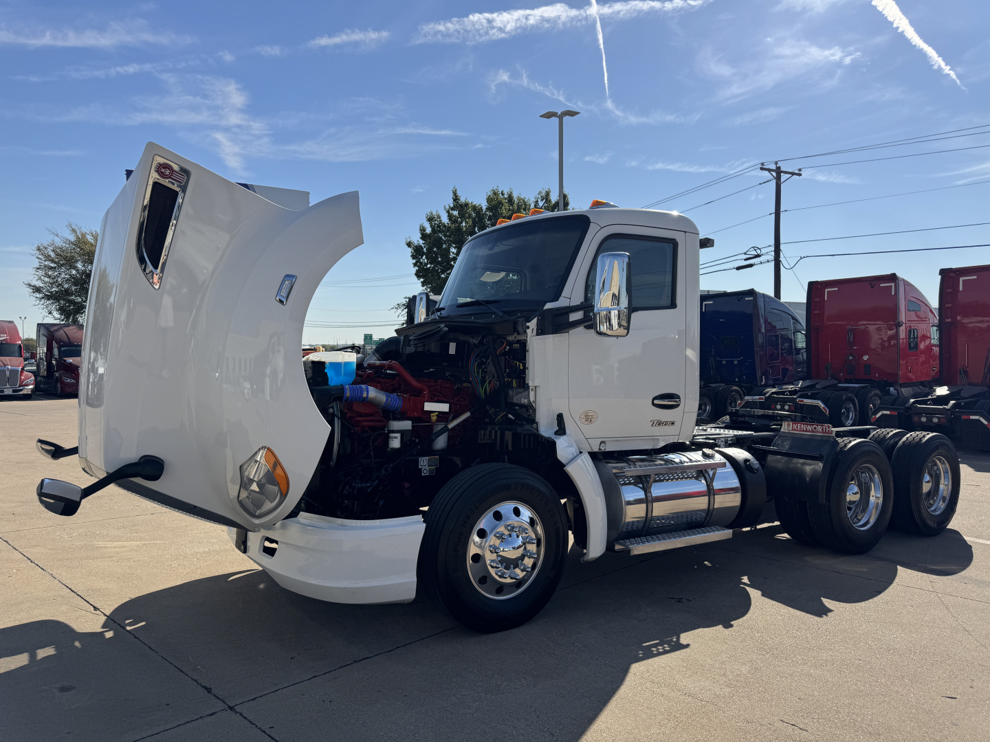 Kenworth T680 truck in a lot with hood open showing engine bay and front left side view.