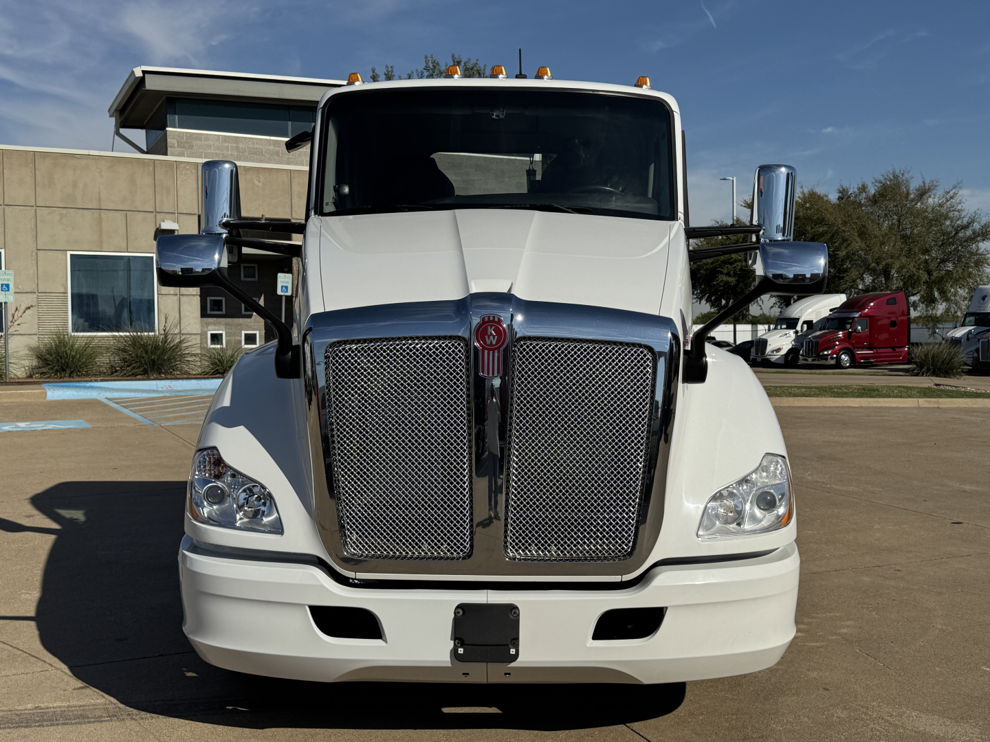 Kenworth T680 front view showing chrome grille, headlights, and white cab with large windshield; no visible text on components.
