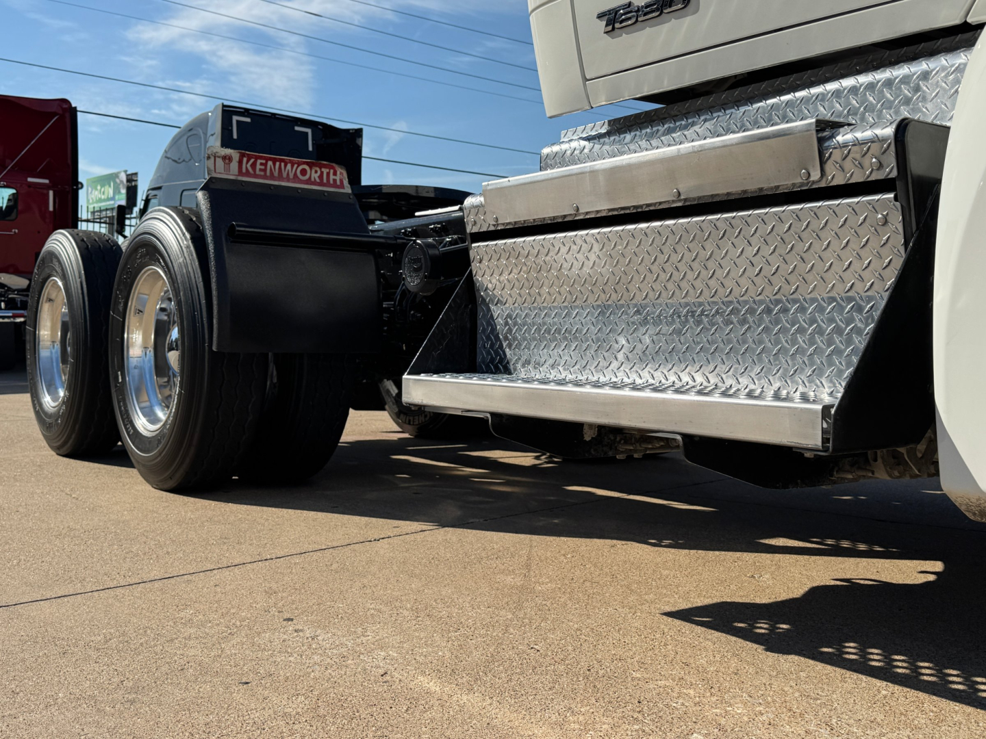 Kenworth T680 truck rear/side view showing chrome diamond plate toolbox, dual rear wheels, and wheel wells.