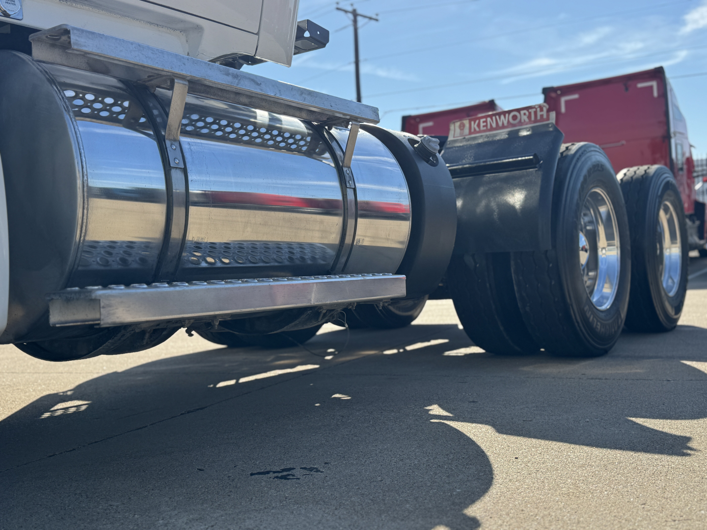 Kenworth T680 undercarriage showing chrome fuel tank and dual rear axles with tires and frame.