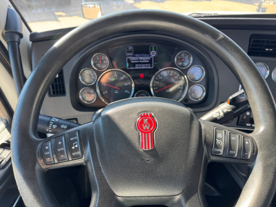 Kenworth T680 cockpit showing steering wheel and instrument cluster with gauges and a center display in view.