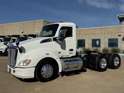 White 2022 Kenworth T680 daycab tractor side view showing fuel tanks and dual rear axles