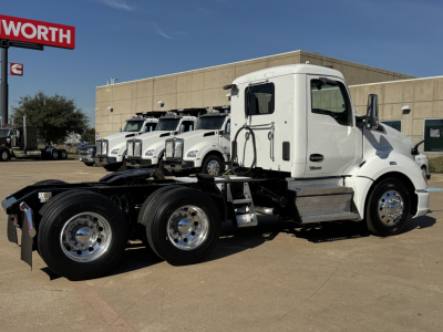 Kenworth T680 conventional daycab truck chassis in a dealership lot with other white trucks in background.