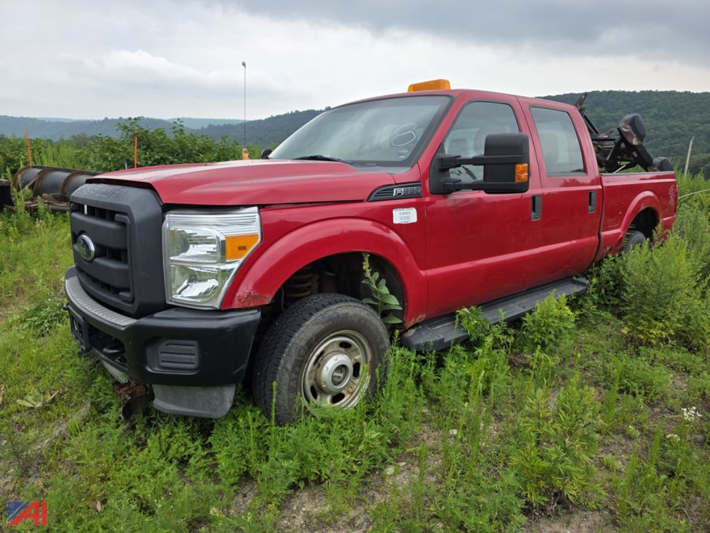 Ford F-350 Super Duty crew cab pickup truck with plow in red, side view, in grassy lot.