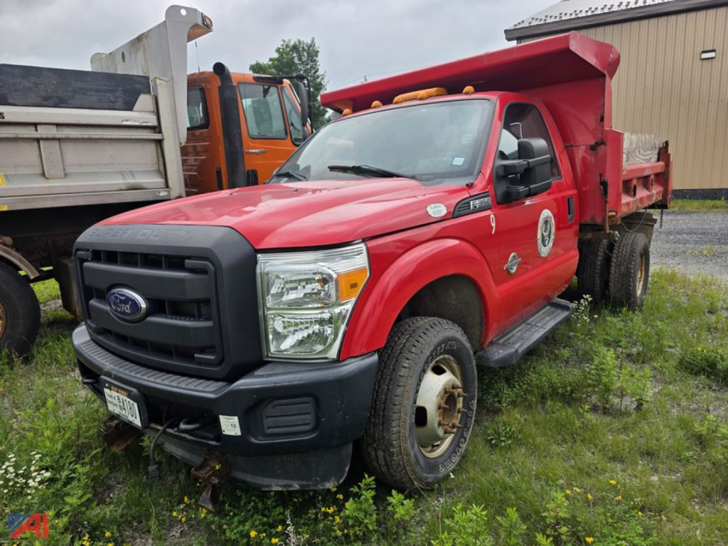 Ford F-350 Super Duty dump truck with plow, red cab, dump bed, front view showing grille and headlamps.