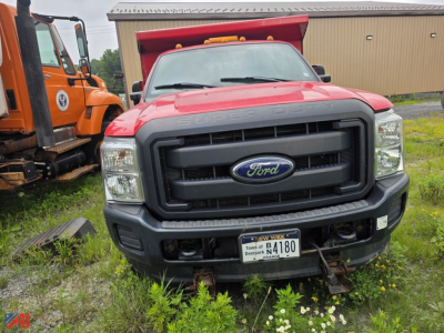 Ford F-350 Super Duty front view dump truck with plow, black grille, New York license plate N4180, field vegetation around bumper