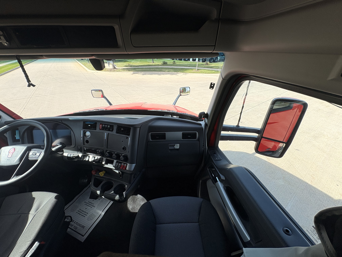 Kenworth T680 interior dash and steering wheel view from driver seat showing gauges and center console.