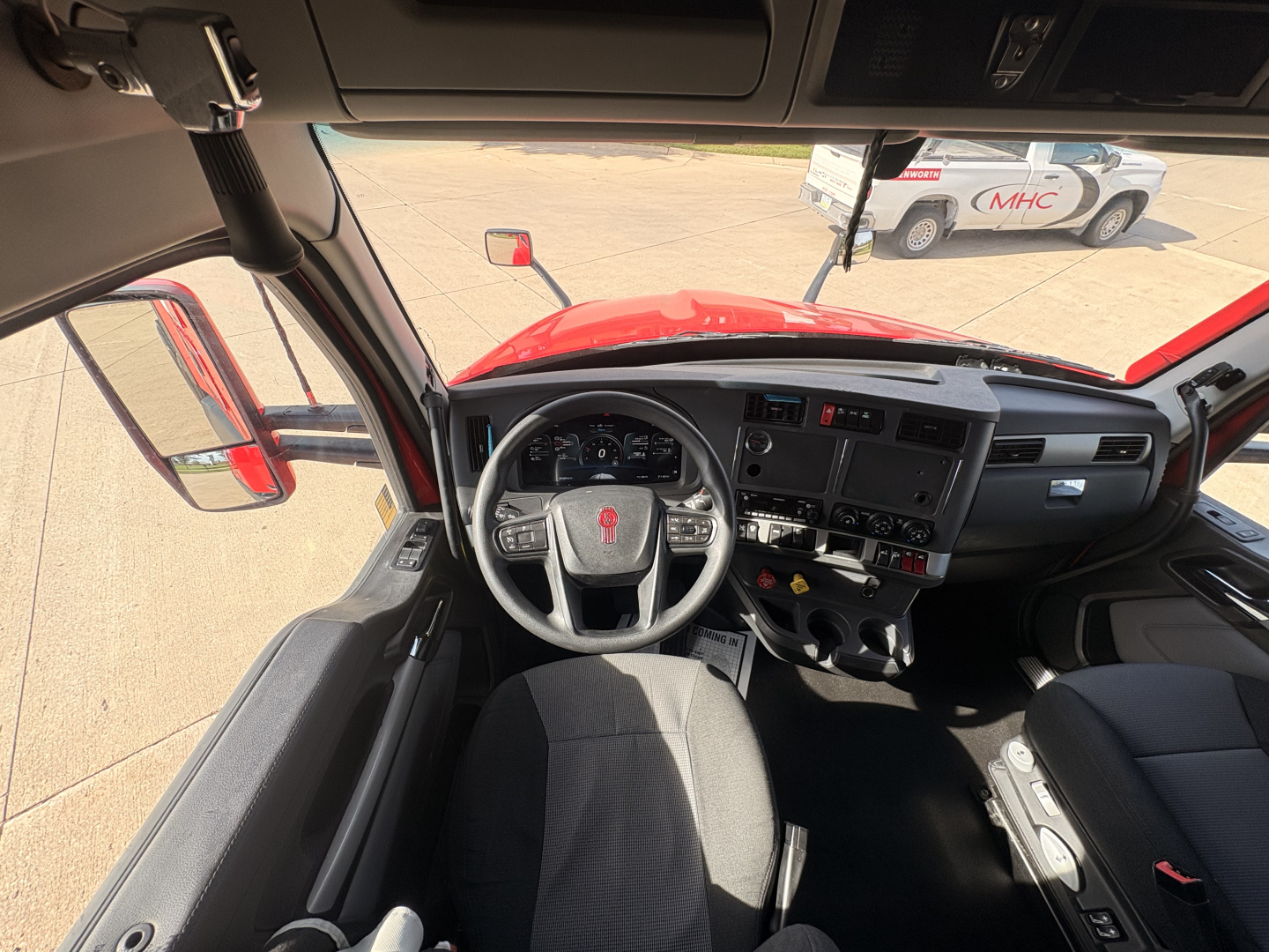Kenworth T680 interior cab dashboard and steering wheel view from driver seat showing controls and gauges.