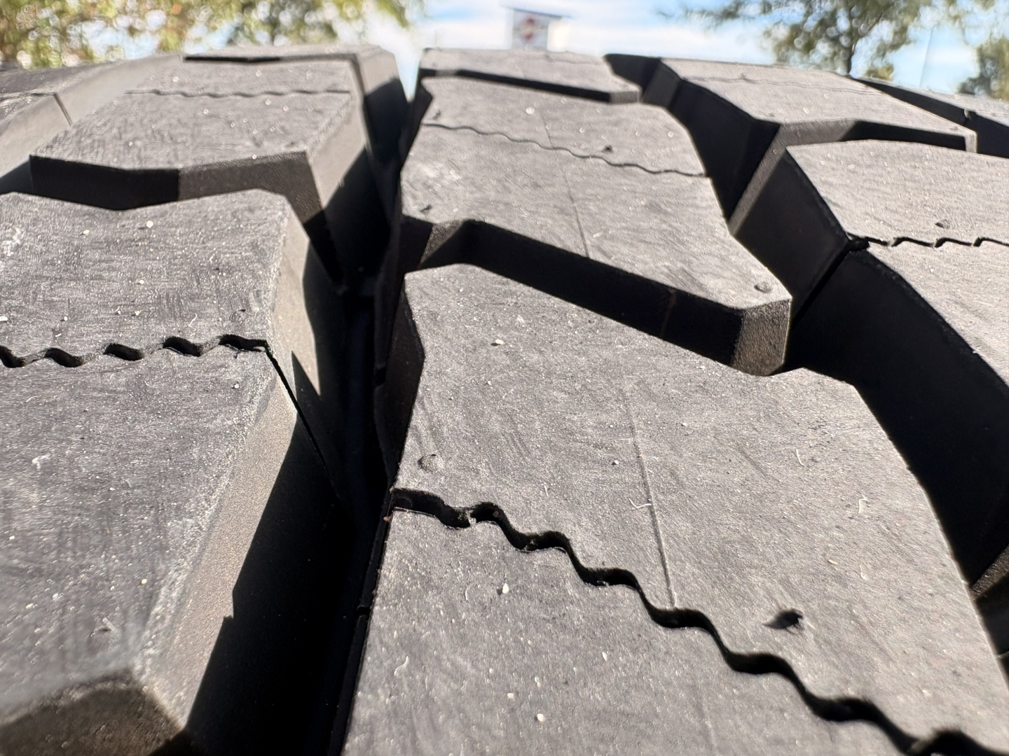 Kenworth truck tire tread close-up view with deep grooves and interwoven pattern.