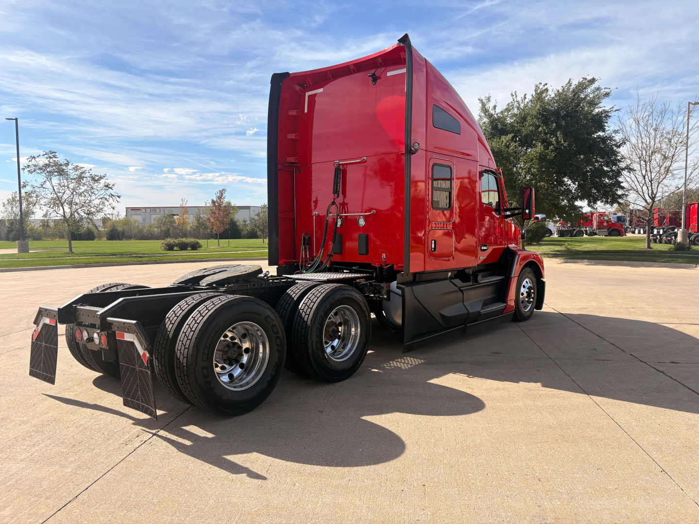 Kenworth T680 sleeper cab with red exterior, viewed from rear-left side, showing dual rear axles and cargo area, no visible text on components.