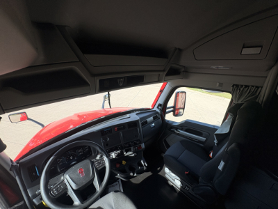 Kenworth T680 cab interior with steering wheel and dashboard visible from passenger side; no visible text on components.