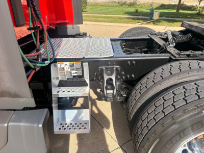 Kenworth T680 chassis showing metal steps, fuel/throttle area, dual rear wheel, with platform and warning labels near the cab.