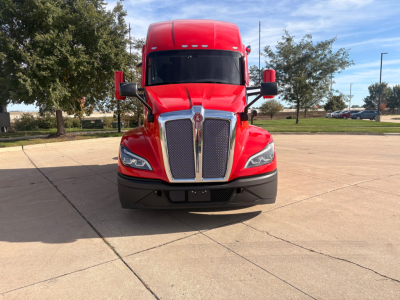 Kenworth T680 front view with red tractor, large chrome grille, headlights, and bumper.