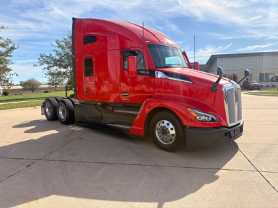 Kenworth T680 tractor unit shown in red with sleeper cab and three rear axles, front view, daytime.