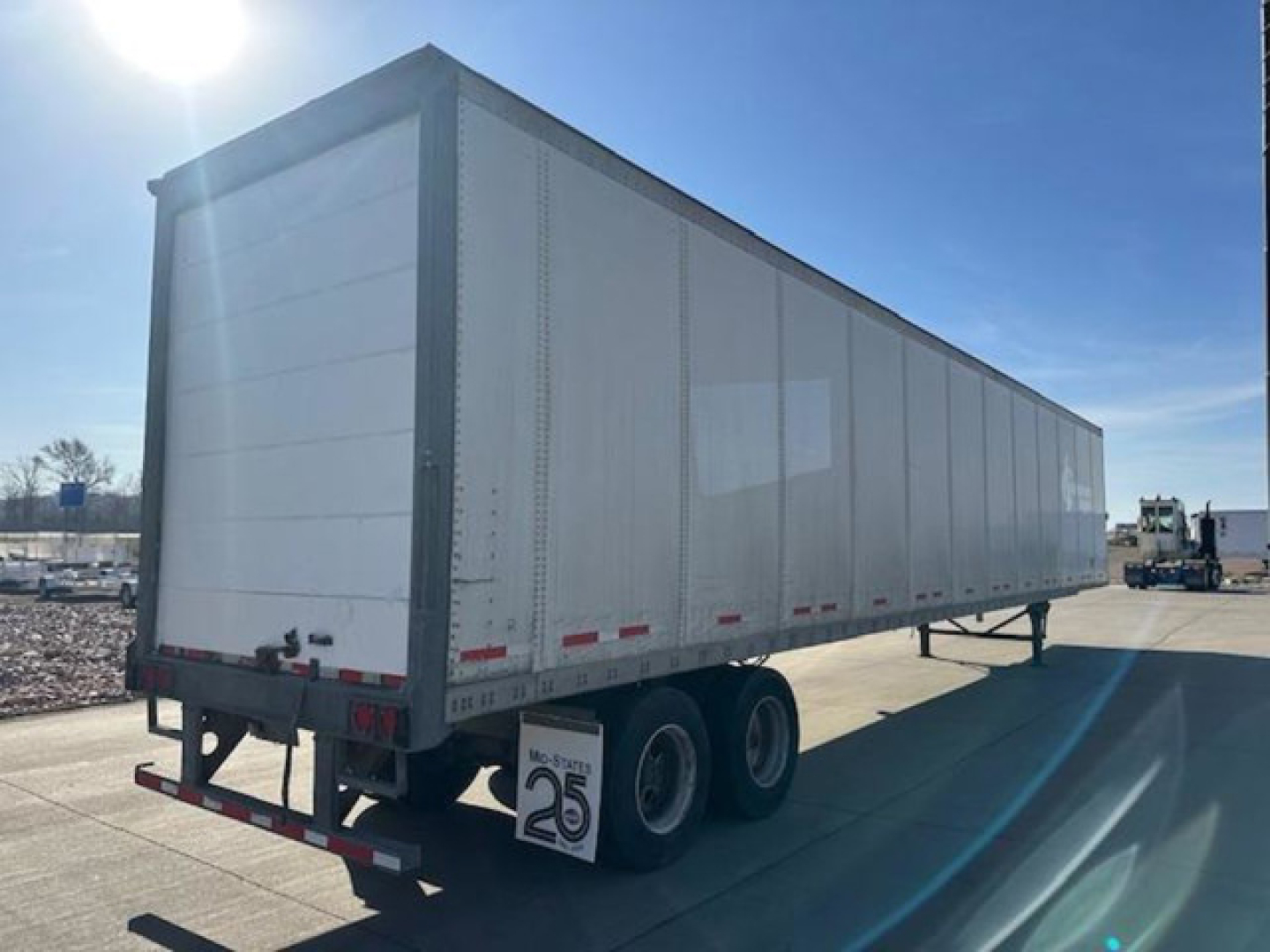 Wabash 53 ft dry van trailer with tandem axle on a sunny day. Visible text includes reflections and a low rear bumper, mud flaps, and a small dealer plate tag.