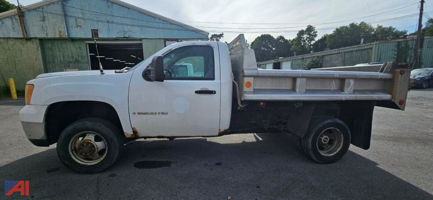 GMC Sierra 3500HD flatbed dump truck side view showing utility bed and plow prep with rear dump bed.