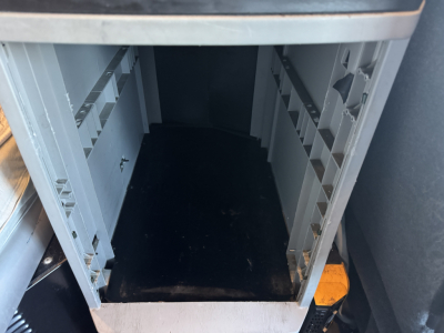 Kenworth T680 cab interior storage area with empty under-seat compartments and open doorway.