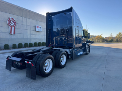 Kenworth T680 truck tractor rear and side view showing sleeper cab, dual rear axles, fifth wheel, and rear mud flaps; exterior is dark blue with chrome accents.