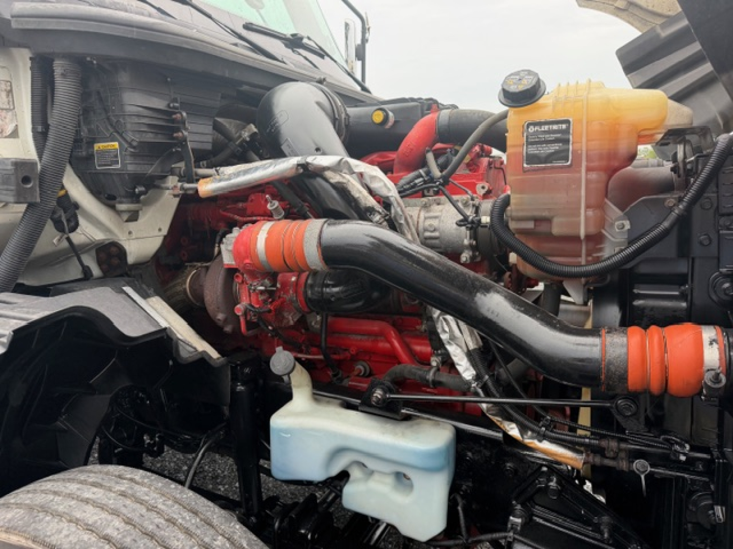 Truck engine bay showing LT625 engine with orange coolant reservoir, blue windshield washer reservoir, and black intake piping.