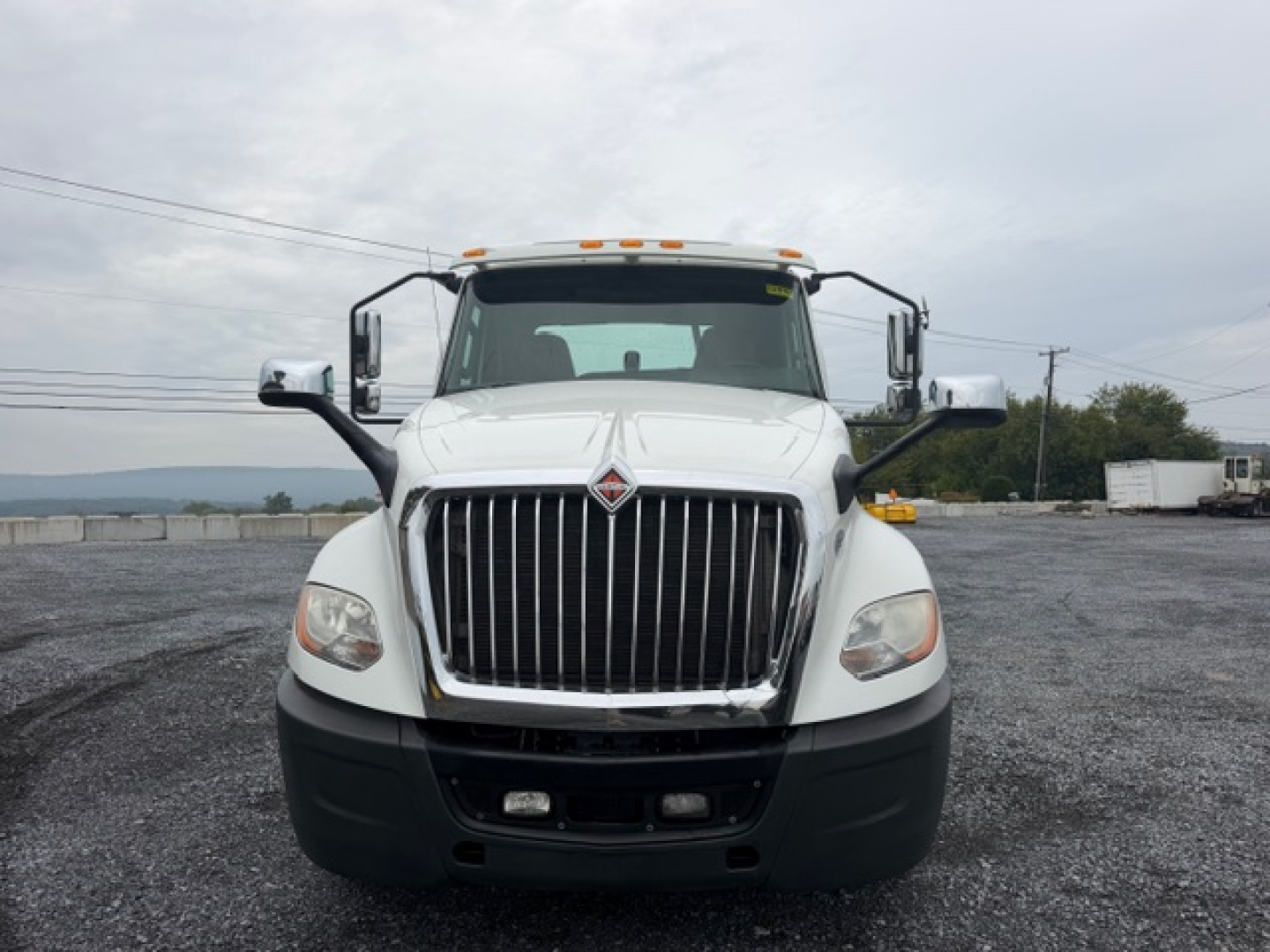 Truck front view of a 2018 International LT625 conventional daycab with large chrome grille, white cab, and black bumper.