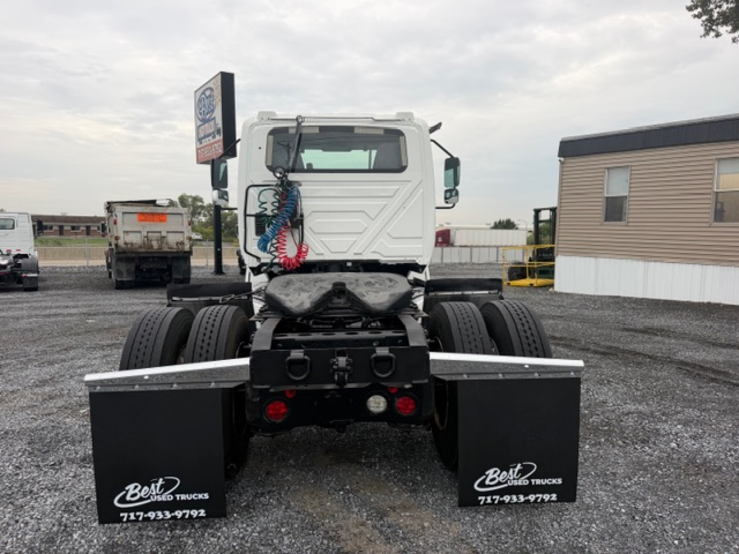 Truck chassis rear view showing fifth wheel area and dual rear axles with black mud flaps and coiled air hoses.