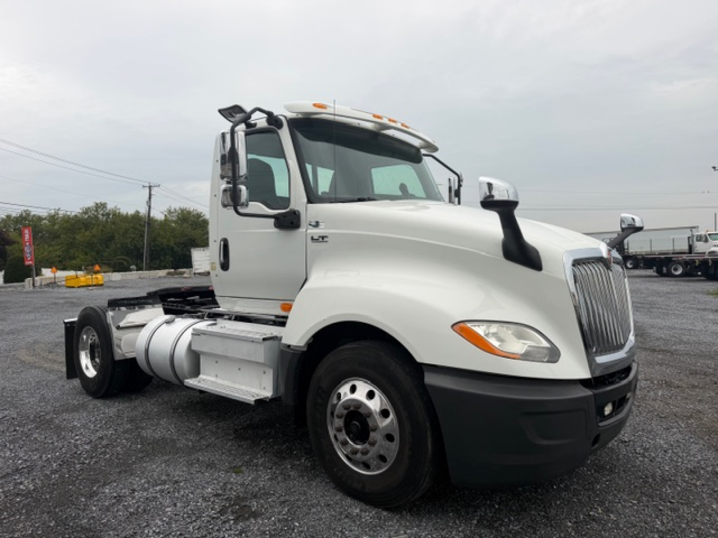 International LT625 daycab truck in white, side view showing cab and front wheel, fuel tank, and steps.