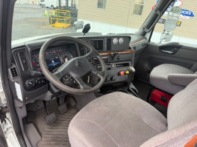 Truck cab interior showing steering wheel, dashboard, and gear shifter with gauges and controls