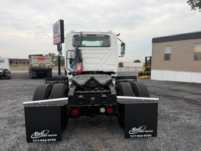 Truck chassis rear view showing fifth wheel area and dual rear axles with black mud flaps and coiled air hoses.