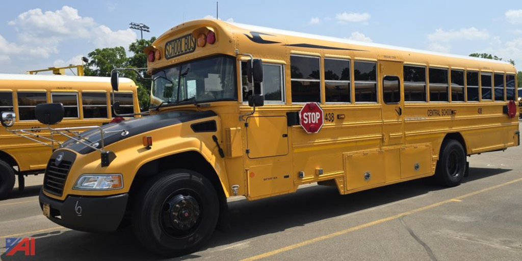 School bus side view showing 2017 Blue Bird Vision yellow bus with STOP sign extended and doors closed.