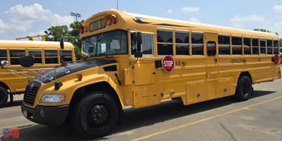 School bus side view showing 2017 Blue Bird Vision yellow bus with STOP sign extended and doors closed.