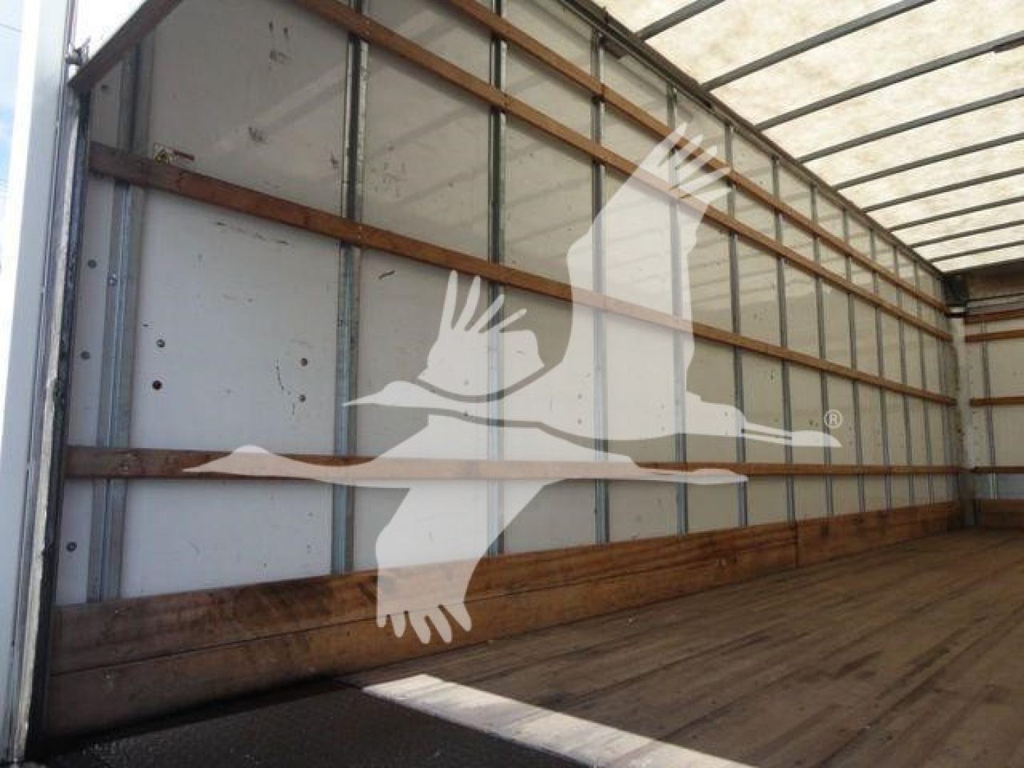 Box truck interior wall of a 2026 Mack MD6 in-service with wooden rails and metallic side panels.