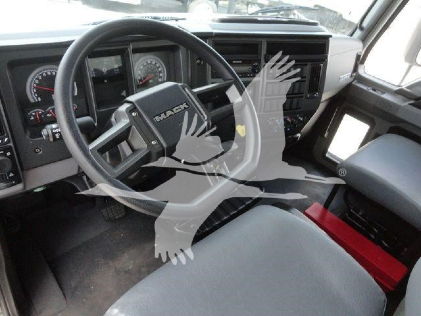 Truck cabin interior of a Mack MD6 showing steering wheel, dashboard, and front seats.