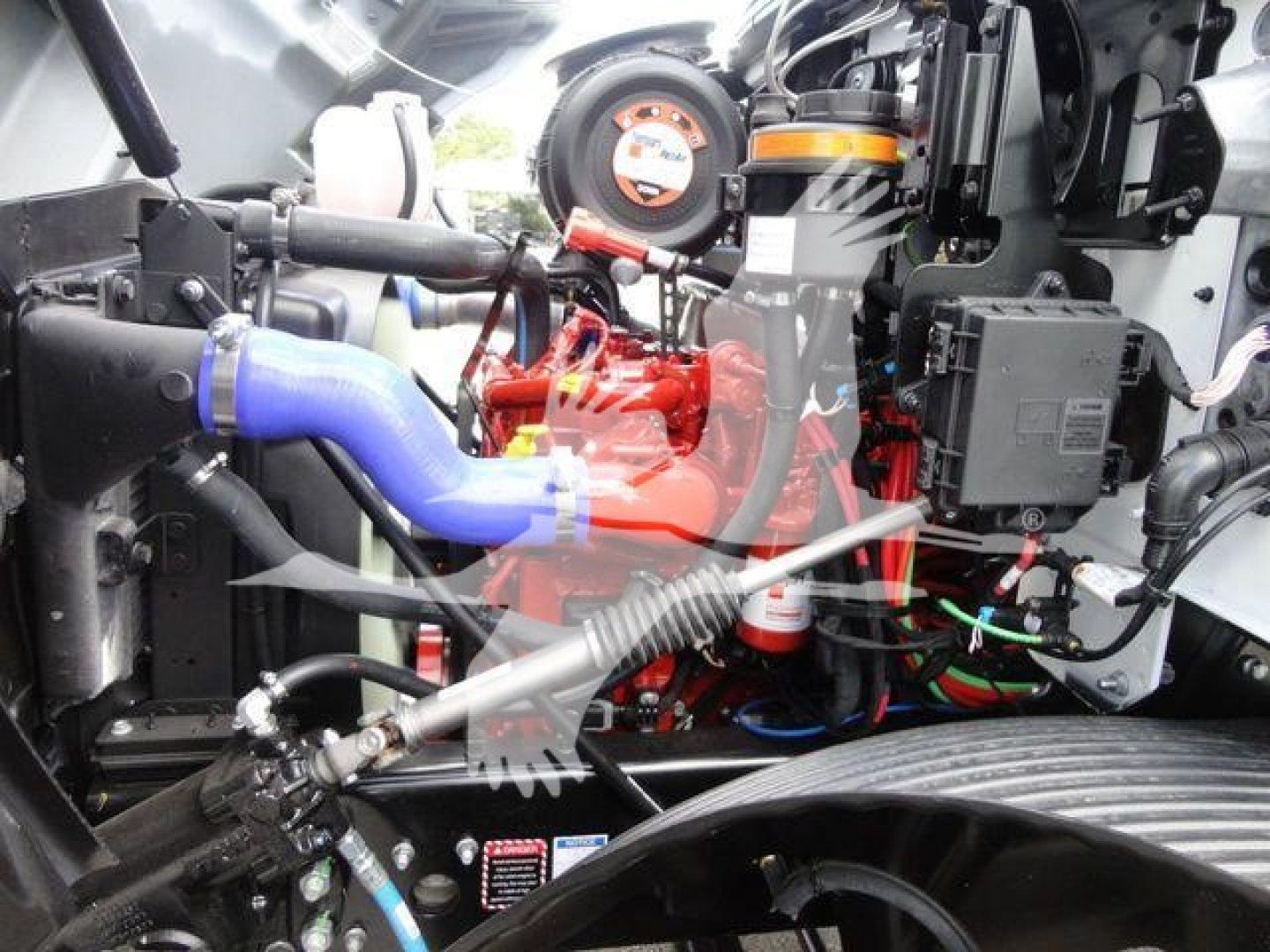 Mack MD6 engine bay showing blue intake hose, red engine block, various hoses and electrical harnesses.