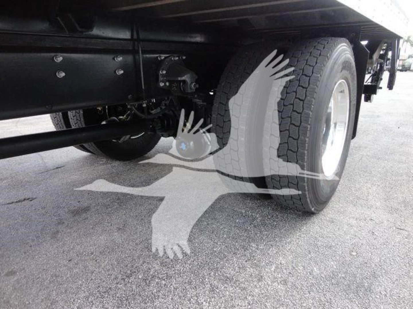 Rear axle area of a Mack MD6 truck showing a large tire, undercarriage, and suspension components.