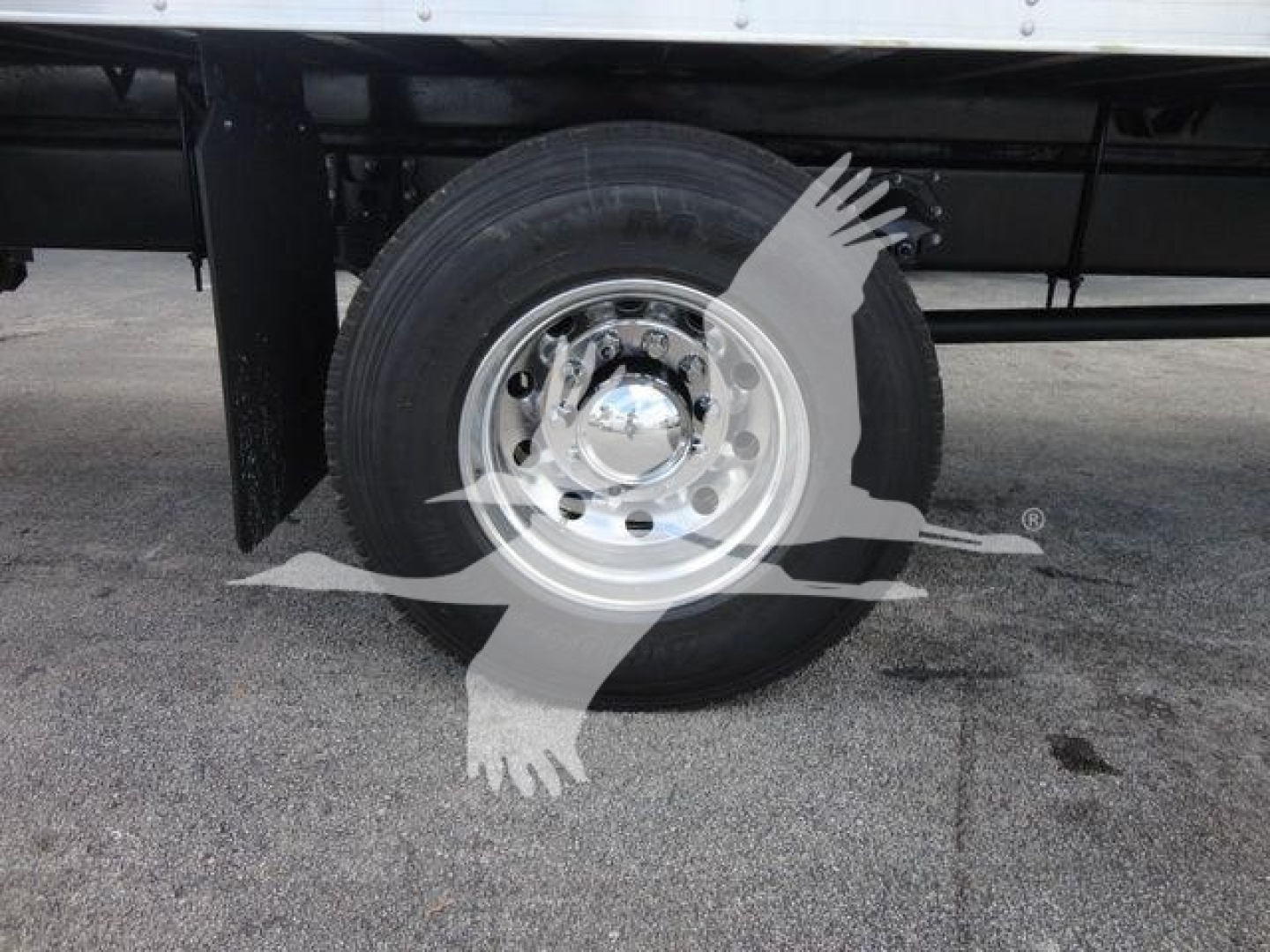 Mack MD6 wheel and tire assembly visible under truck, chrome hubcap, black chassis, in-service ground surface.