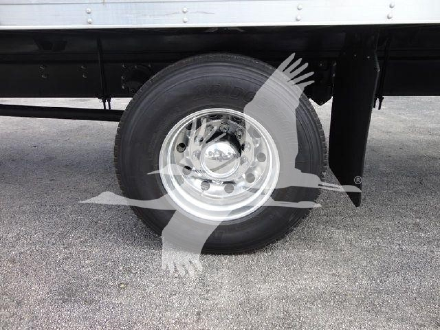 Mack MD6 wheel and tire on truck undercarriage showing chrome hubcap and black chassis.