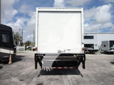 Box truck rear view showing cargo area and undercarriage with a rear bumper and reflective tape in a dealership lot.