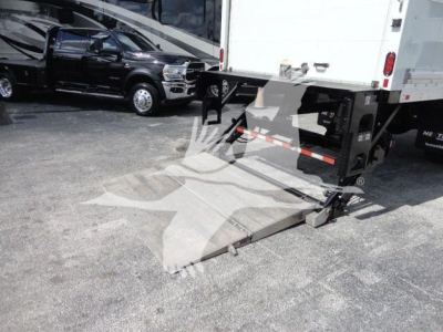 Truck with rear liftgate ramp extended showing box truck undercarriage and loading platform.