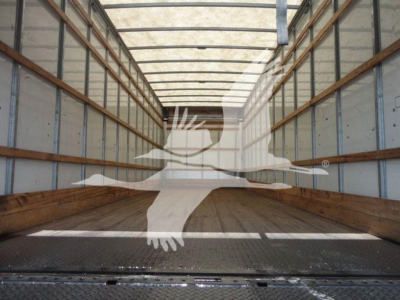 Empty Mack Md6 truck trailer interior showing long cargo area with wooden side rails and metal floor; watermark silhouette overlay across the image.