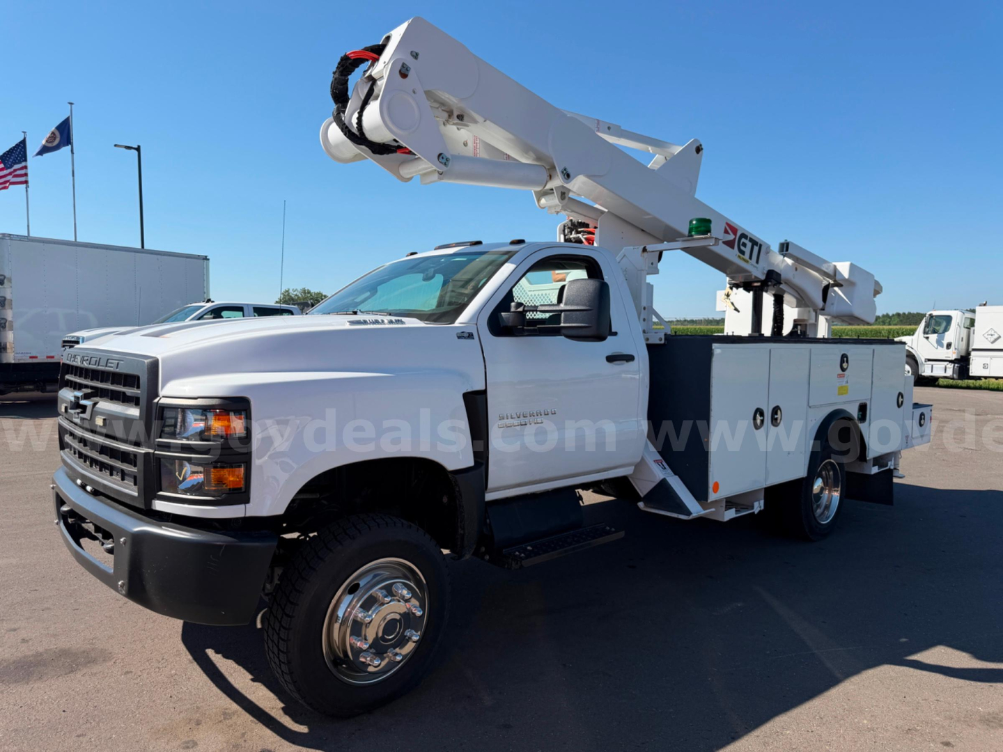 Front three-quarter view of a white 2020 Chevrolet Silverado 6500HD bucket truck with boom elevated, utility compartments along the side, dual rear wheels, and a black front bumper.