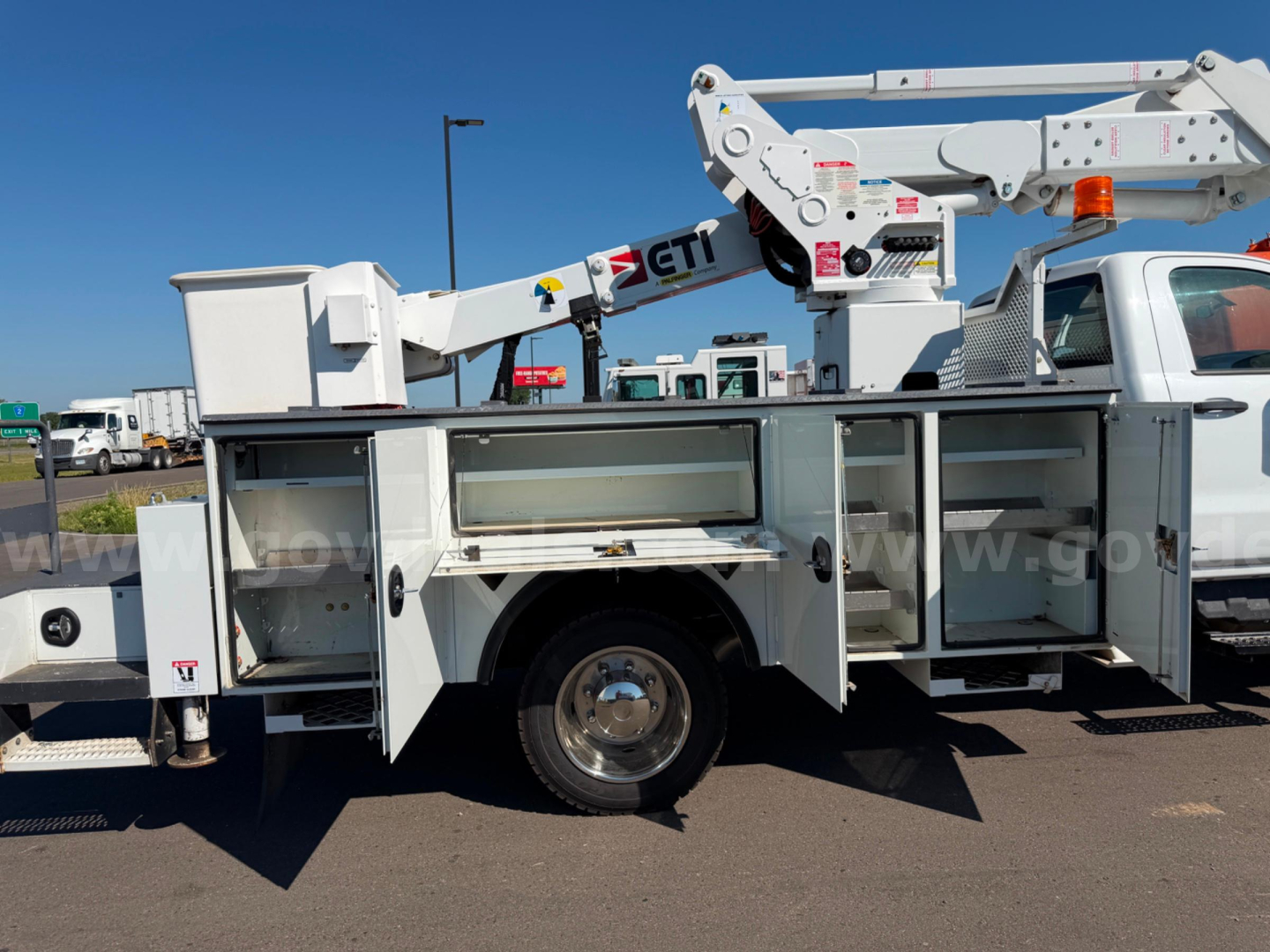Truck body with service compartments and crane on a Chevrolet Silverado 6500HD bucket truck showing multiple storage cabinets and a white utility boom.